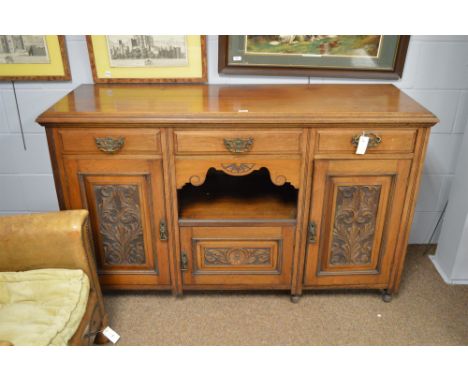 A Victorian carved mahogany side board, the three drawers above panelled cupboards, one with sliding bottle shelf, flanking a