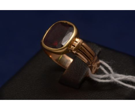 A garnet ring, the single stone in yellow metal mount.