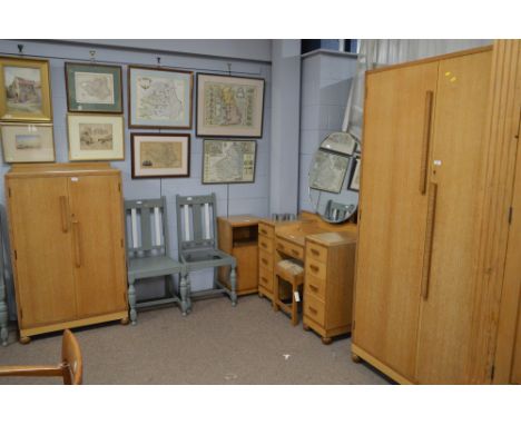 A mid 20th Century light oak bedroom suite, comprising: a gents wardrobe, the doors opening to reveal sliding shelves and han