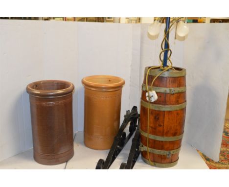 A pair of wrought iron scrolling wall brackets; two salt glazed stick stands; and a brass bound barrel converted to a lamp.