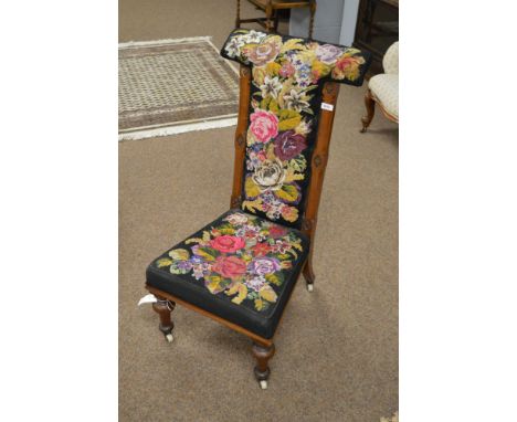 A Victorian mahogany and tapestry work prie dieu chair on turned front legs terminating in castors.