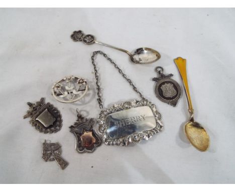 A good collection of silver items to include brooch, fob medals, enamel spoon, sherry label and cross