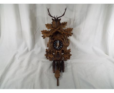 A Black Forest cuckoo clock decorated with animal, bird and foliage carving