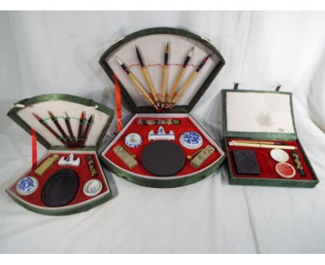 Three Chinese calligraphy / writing sets containing ink sticks, ink stones and brushes made from goats tails, stone seals and