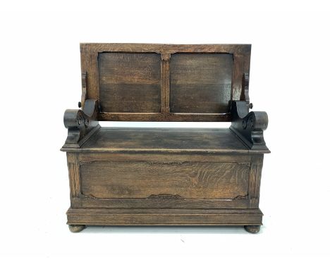 Early 20th century oak monks bench, the folding panelled back rest over hinged seat, panelled front and sides, raised on bun 