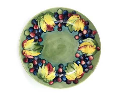William Moorcroft, a Leaf and Berry plate, circa 1930, green ground with broad rim, impressed marks and facsimile signature, 