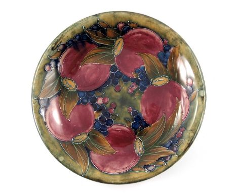 William Moorcroft, a Pomegranate on ochre plate, circa 1914, circular with everted rim, impressed marks and underglaze green 