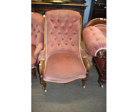 Victorian button back armchair with scrolled arms and short cabriole legs raised on casters, upholstered in a pink fabric