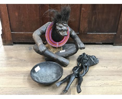 An African carved seated figure with necklace and bowl on folding tripod legs carved with elelphants