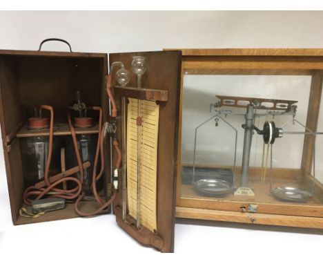 An oak cased beam balance scale and a mahogany box containing medical fluid draining jars.
