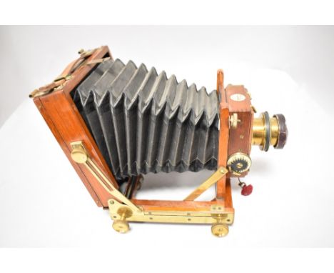 A Thornton Pickard mahogany case field camera having brass lens with two plate holders and cloth light cover. Plate size is 4