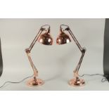 A LARGE PAIR OF COPPER ANGLE POISE LAMPS.