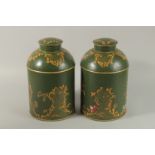 A PAIR OF GREEN TOLEWARE CIRCULAR CANISTERS AND COVERS. 34cm high.