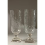 A PAIR OF GLASS STORM LANTERNS on square stepped bases. 34cms high.