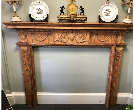 An antique Georgian fireplace carved in pine. This original, large and exquisitely carved fire surround features dog-leg jamb