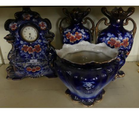 An early 20th Century ceramic three piece floral decorated clock garniture together with a similar jardiniere