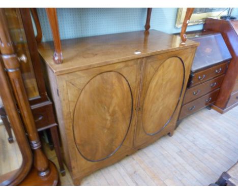 A 19th Century mahogany two door cupboard the oval panelled doors opening to reveal a shelved interior, raised on bracket fee