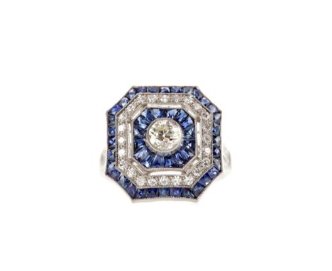 SAPPHIRE AND DIAMOND RING, set with a central round brilliant cut diamond surrounded by calibre cut sapphires and smaller dia