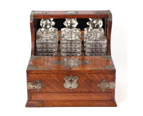 A late 19th century oak three bottle Tantalus, the front section opening to reveal compartments containing glasses with hidde