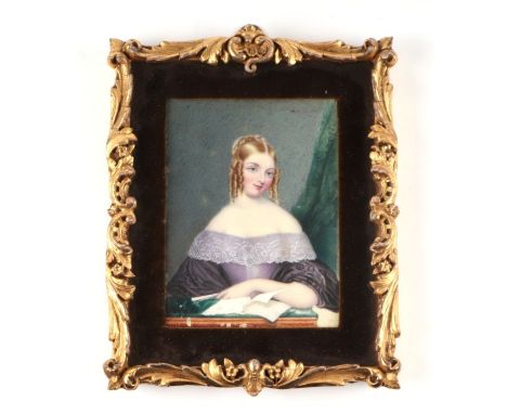 A portrait miniature on ivory depicting a young girl wearing a lavender dress reading a book, framed and glazed, the miniatur