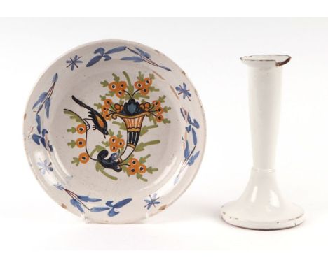 An 18th century faience dish decorated with a bird and cornucopia, 23cms diameter; together with a faience candlestick, 20cms