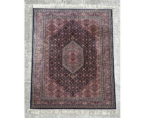 A Persian Kashan rug with geometric design on a pink ground, 170 by 237cms.Condition ReportSome staining and light wear other