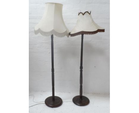 STAINED OAK STANDARD LAMP
raised on a circular base with a turned column and a shaped cream shade and another similar standar