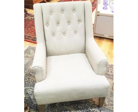 A contemporary armchair upholstered in ecru linen, with button back, raised on square section tapering oak supports, 93 x 70 