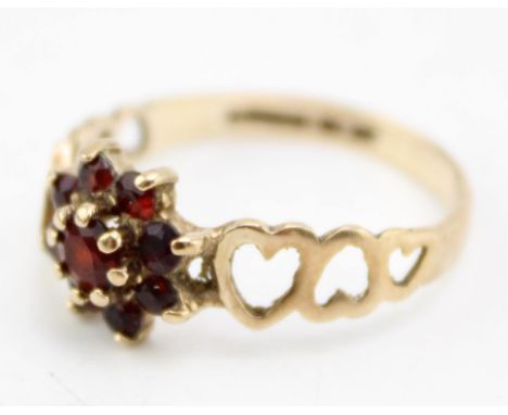A 9ct gold and garnet flowerhead ring with heart detailing to the shoulders, size Q/R, 2.0g