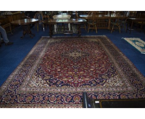 A Large Persian Carpet In The Meshad Style, with a central floral motif with corresponding blue border. Slightly worn. 158x11