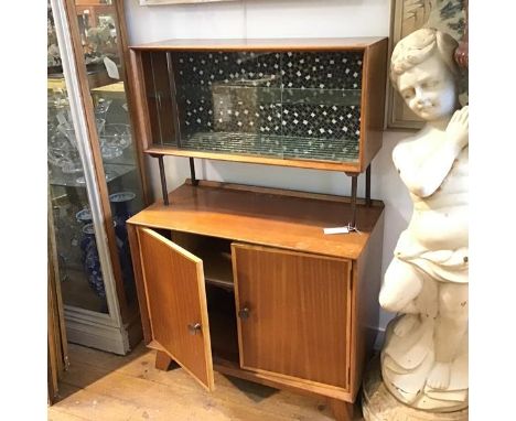 A 1950s/60s teak two section cocktail cabinet with twin sliding glazed panel doors enclosing a mosaic style panel back and mi