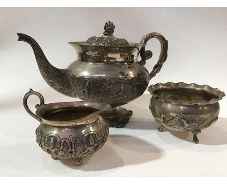 An Indian white metal three piece tea service comprising teapot with C scroll handle to side, with chased finial and panels t