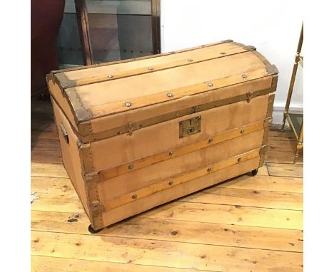 A 19thc oak metal bound dome top saratoga style trunk, with paper lined interior, raised on ball castors (58cm x 83cm x 50cm)