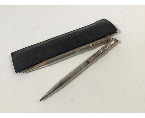 A leather pouch containing two silver yard o lead propelling pencils with engine turned decoration (2)