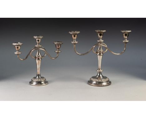 GRADUATED PAIR OF THREE LIGHT ELCTROPLATED CANDELABRA, each with twin scroll arms, circular base and floral embossed borders,