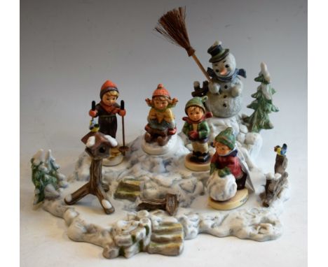 A Hummel Goebel Christmas advertising window display stand and figures, including Snowman, Skier, Tobogganist, It's Cold, Fir