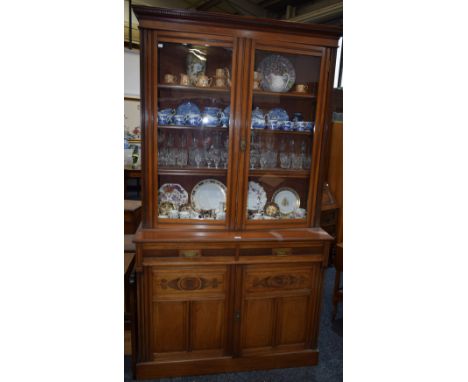 An Arts and Crafts library bookcase, dentil cornice above a pair of glazed doors enclosing shelves, the projecting base with 