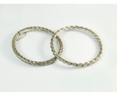 SILVER BANGLES. A spiral twist hinged oval bangle & one other silver spiral bangle.  Note that all items in this auction are 
