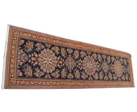 A Qum runner, with three floral medallions on a blue ground, 294 x 82cms.