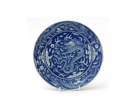 A Chinese blue and white dragon dish, Qing, decorated with a central dragon chasing a flaming pearl within cloud scroll, the 