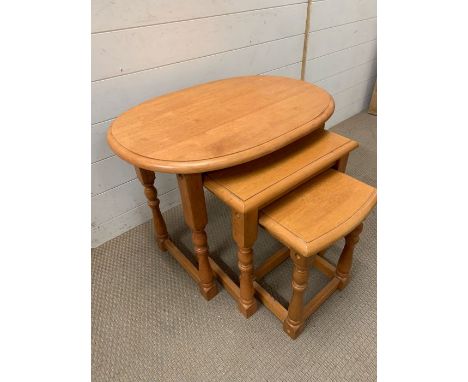 A nest of three light oak tables on turned legs 