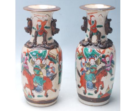 A pair of early 20th Century Chinese ceramic vases having a flared top with twin handles over hand painted polychrome decorat