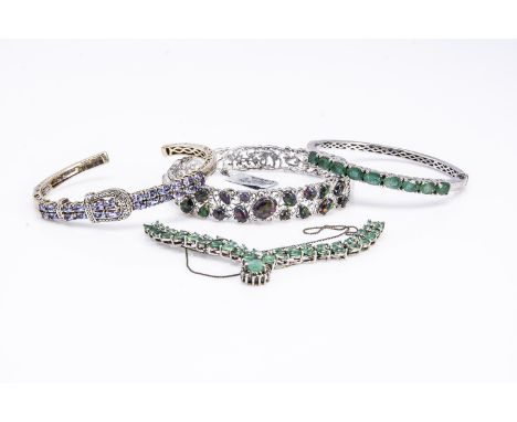 A silver diamond and tanzanite bangle,  an emerald bangle in silver an emerald fringe necklace in silver and a synthetic opal