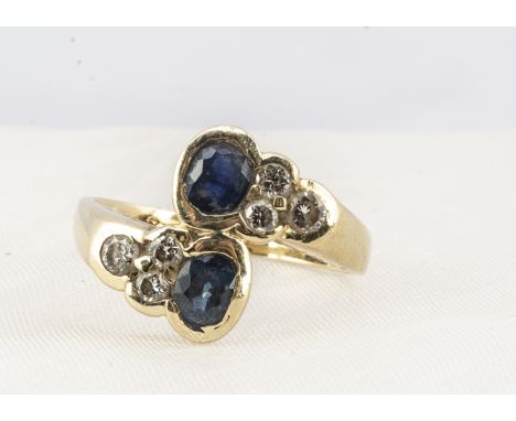 A 14ct sapphire and diamond dress ring,  oval mixed cut sapphires in a cross over setting with diamond set shoulders, ring si