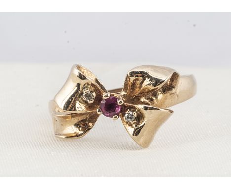 A 14k ruby and diamond bow dress ring, the central ruby in claw setting flanked by two small diamonds in a bow setting on a t