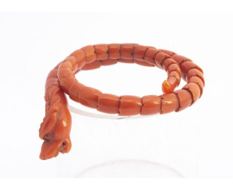 A 19th Century Chinese coral carved articulated dragon bangle, with carved dragon's head, scaled snake like body and shaped t