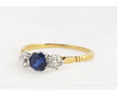 A sapphire and diamond 18ct gold three stone dress ring, the central mixed round cut, weighting 0.65cts, flanked by two brill