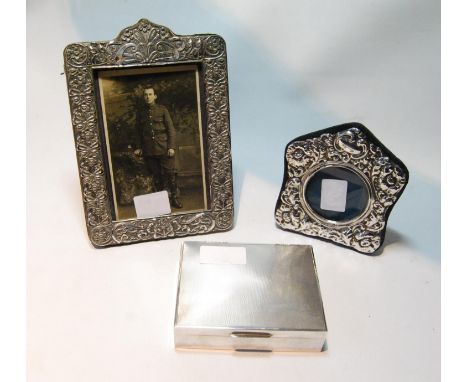 Silver engine-turned cigarette box and two embossed silver photograph frames.&nbsp; (3) 