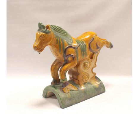 Chinese Ming-style pottery roof tile in the form of a galloping horse with green and ochre glazes, 26cm high. 