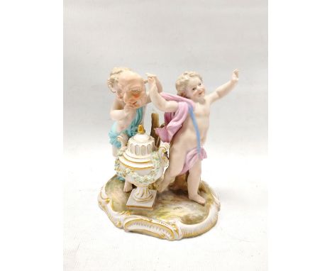 19th century Meissen porcelain figure group of two putti playing with a mask standing on a plinth base with urn, decorated in